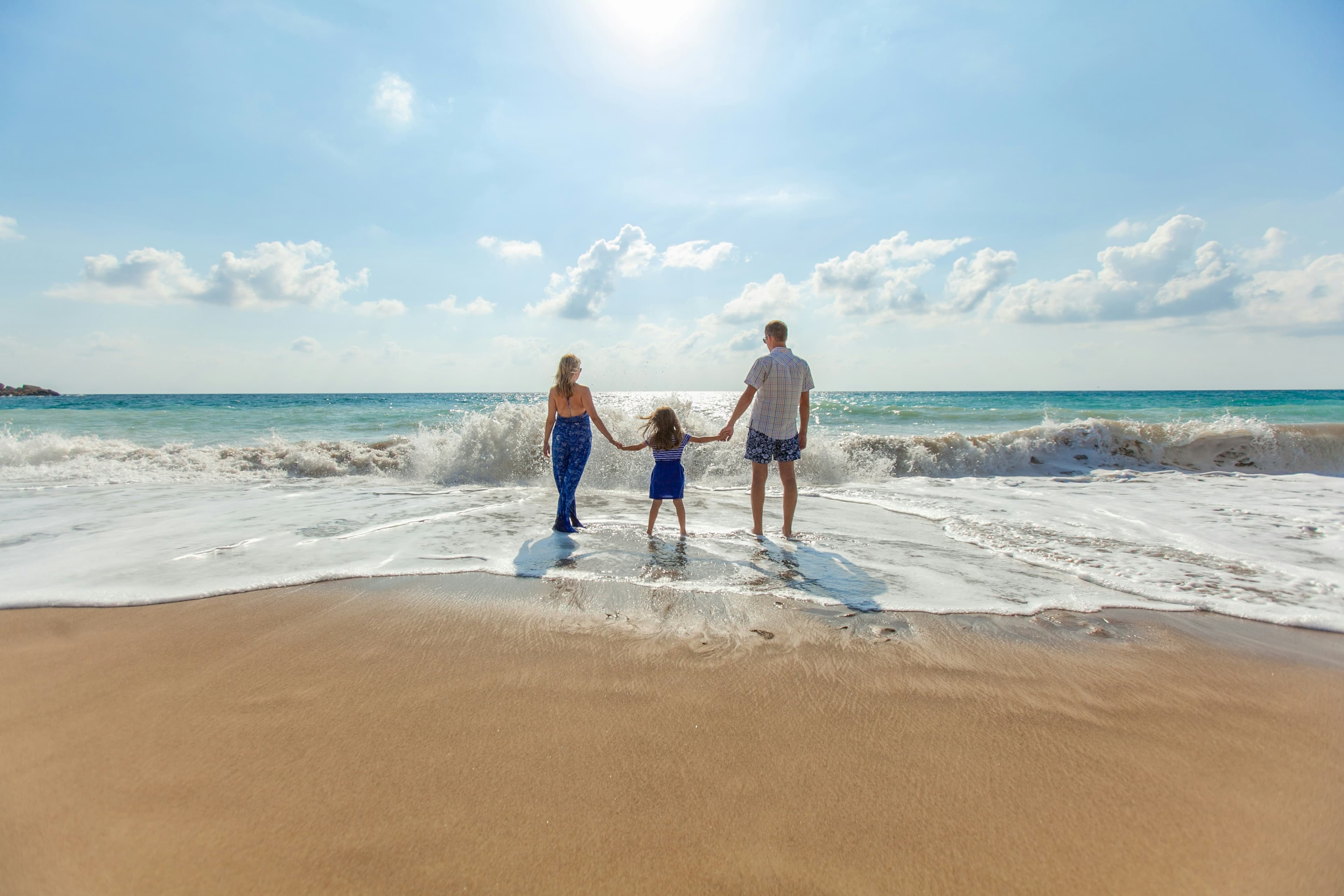 A family walking together along the shoreline, hand in hand
