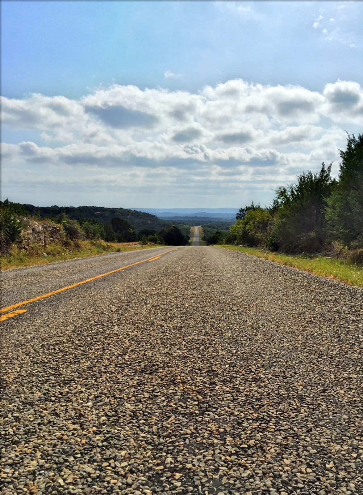 A quiet Texas Hill Country road stretching toward the horizon